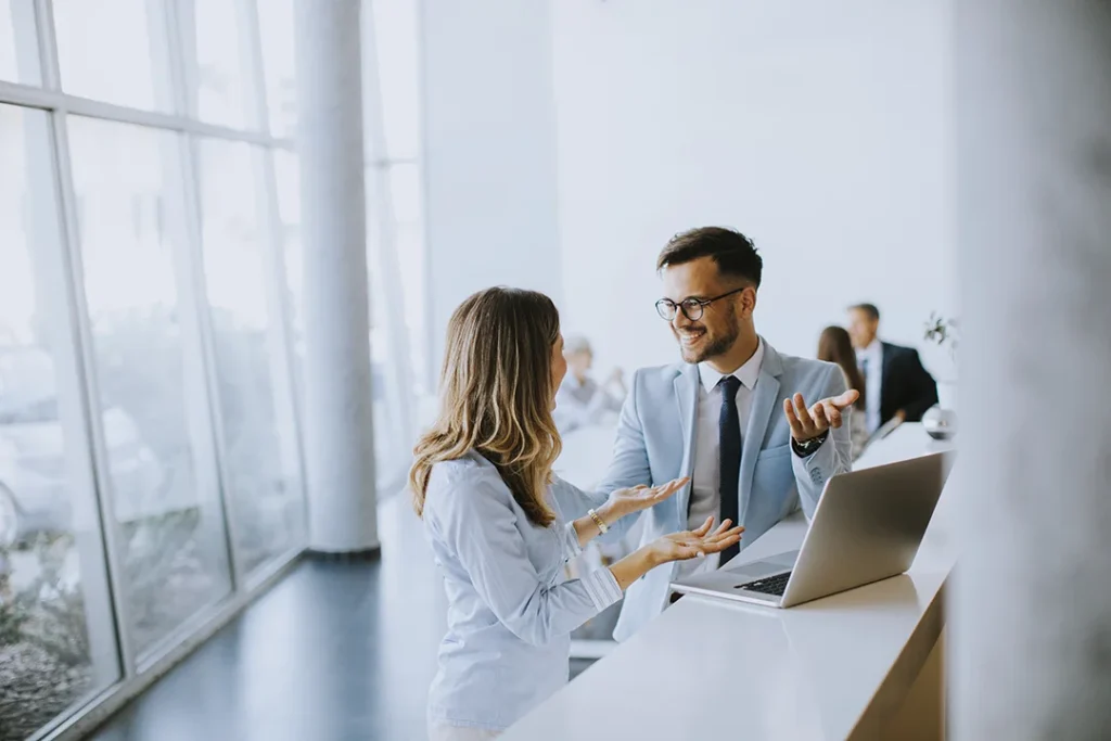 young-business-couple-working-discussing-by-laptop-office-front-their-team